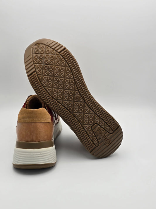 Modischer Sneaker mit braun-beiger Sohle und Wildlederdetails auf weißem Hintergrund
