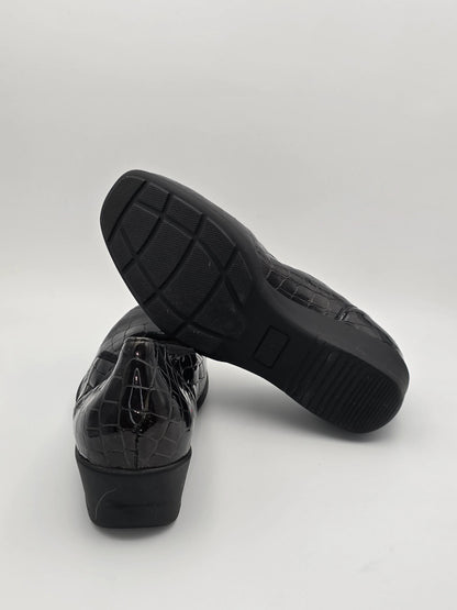 Schwarze Damenschuhe mit Kroko-Prägung und rutschfester Sohle auf weißem Hintergrund