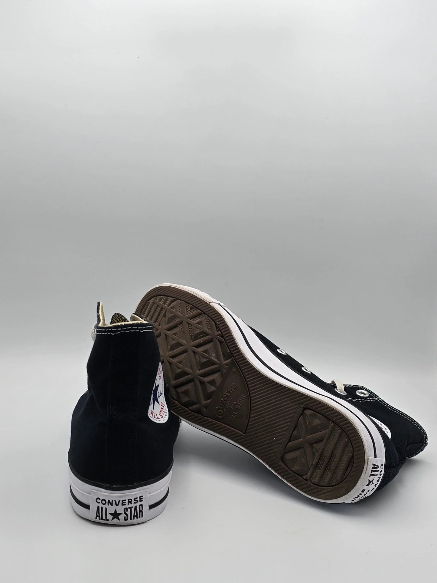 Schwarze hohe Sneaker mit weißer Sohle und Converse All Star Logo, auf weißem Hintergrund