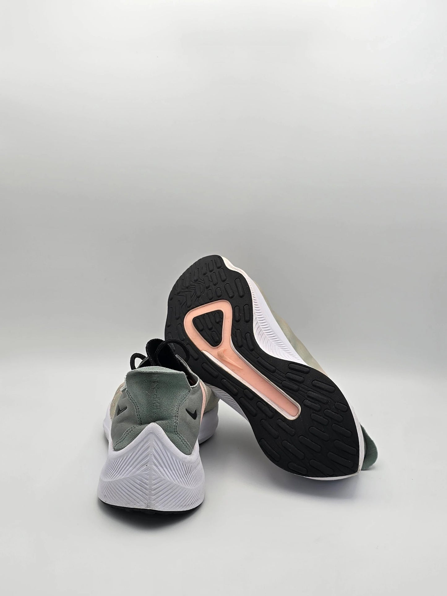 Moderne Sneaker mit grün-weißem Obermaterial und schwarzer, profilierter Sohle auf weißem Hintergrund