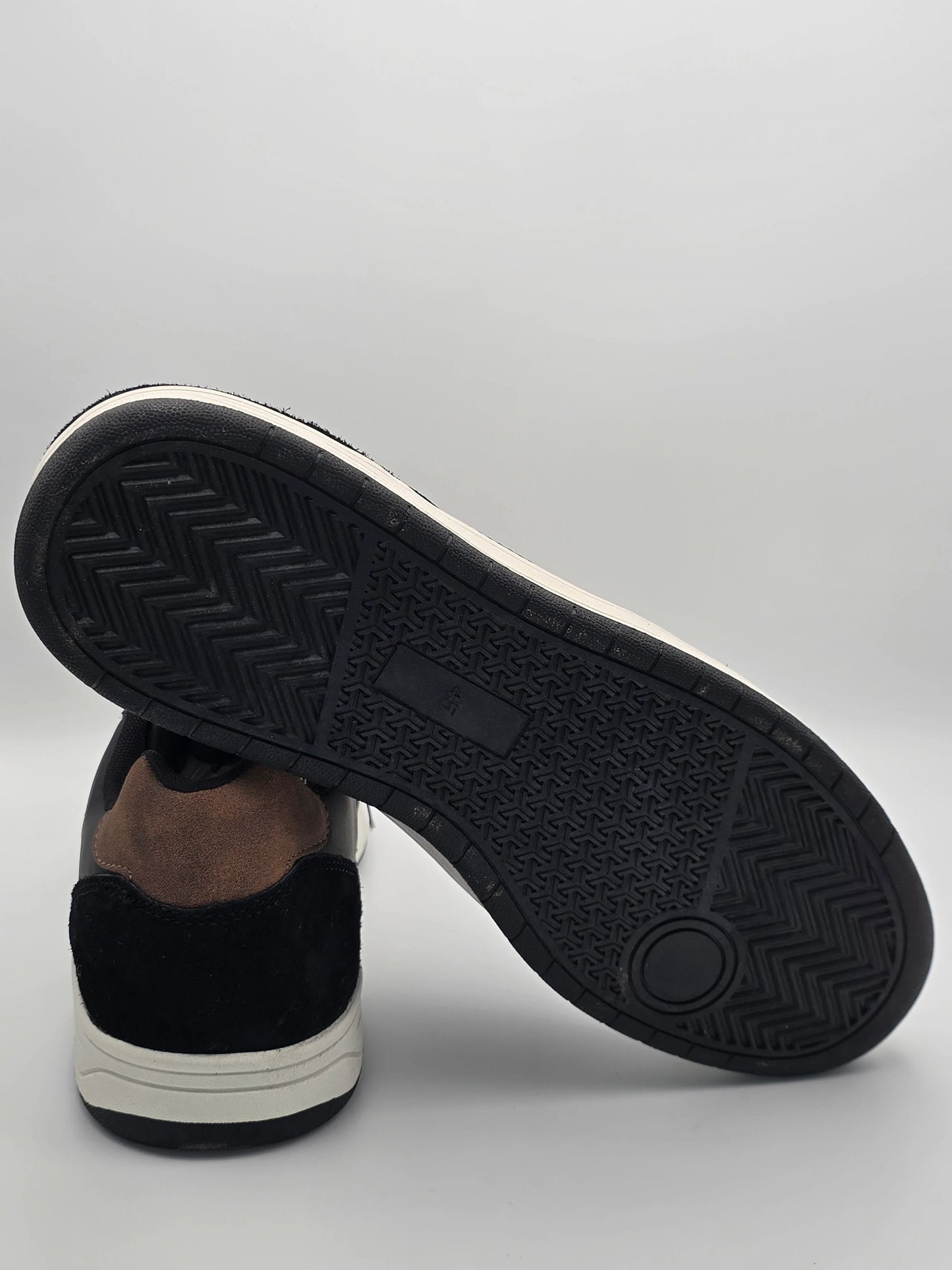 Nachhaltiger Sneaker in Schwarz und Braun mit detailierter Gummisohle auf weißem Hintergrund