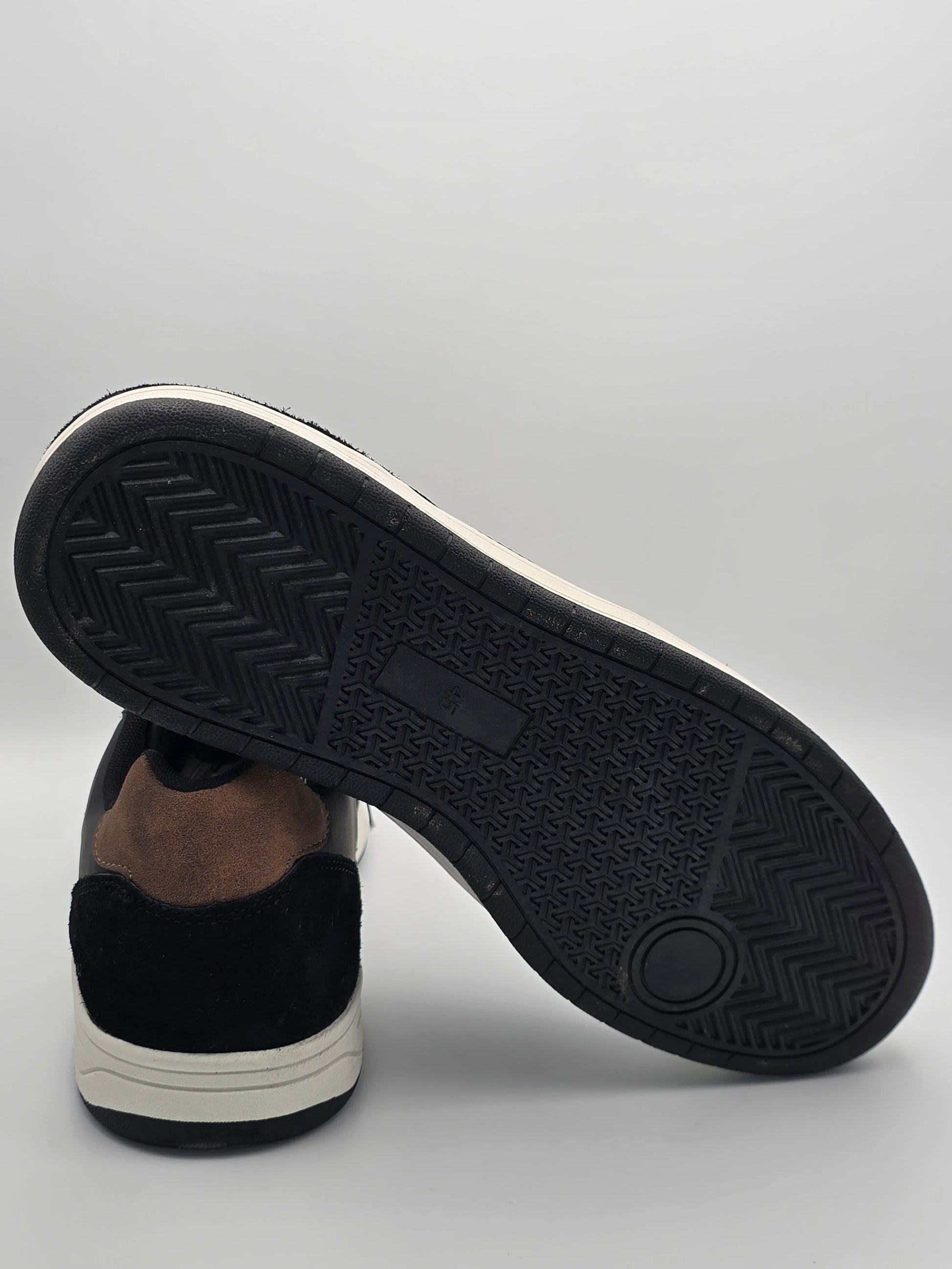 Nachhaltiger Sneaker in Schwarz und Braun mit detailierter Gummisohle auf weißem Hintergrund