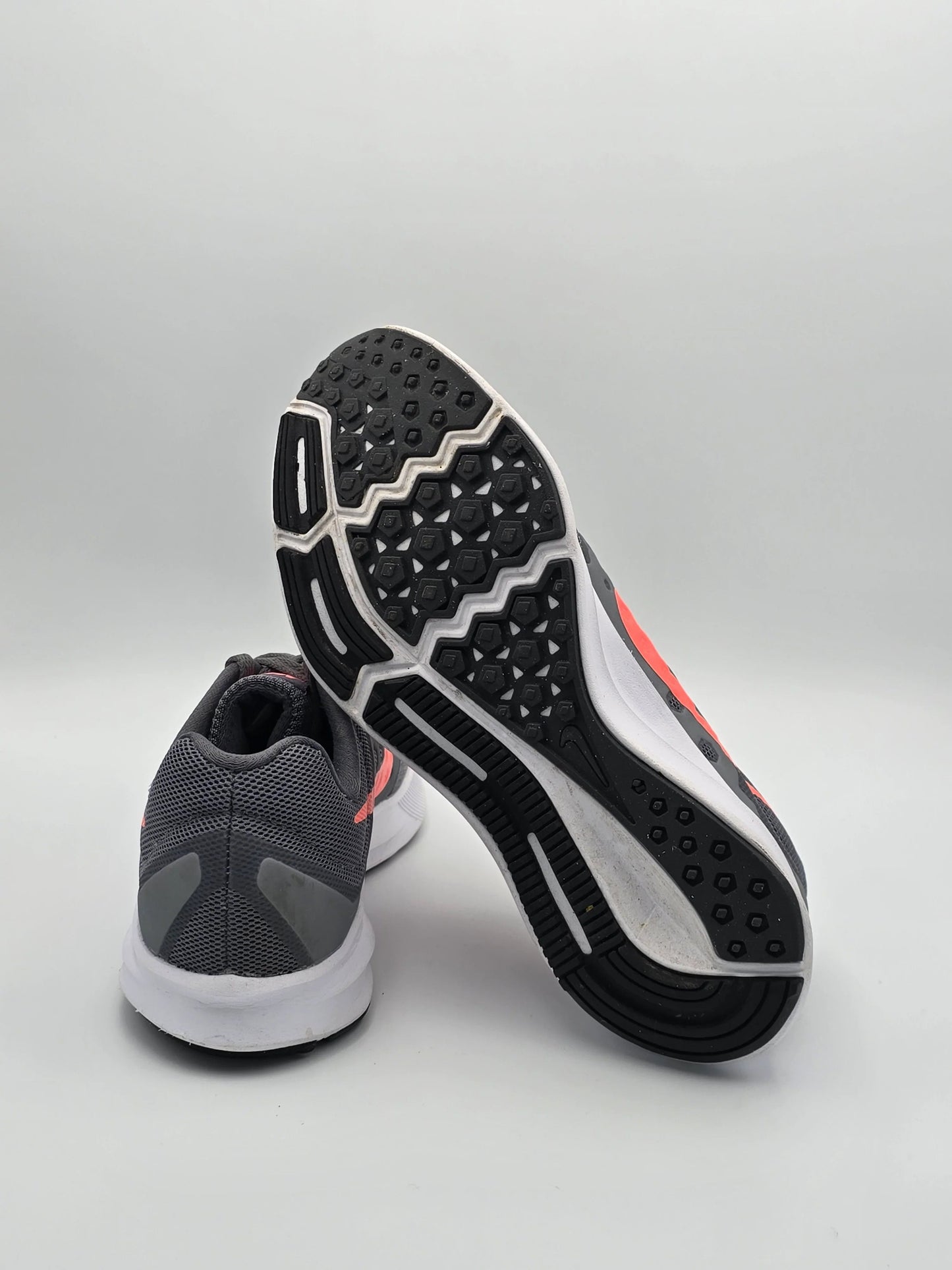 Graue Laufschuhe mit weißer Sohle und pinken Details auf weißem Hintergrund, sportliche Mode