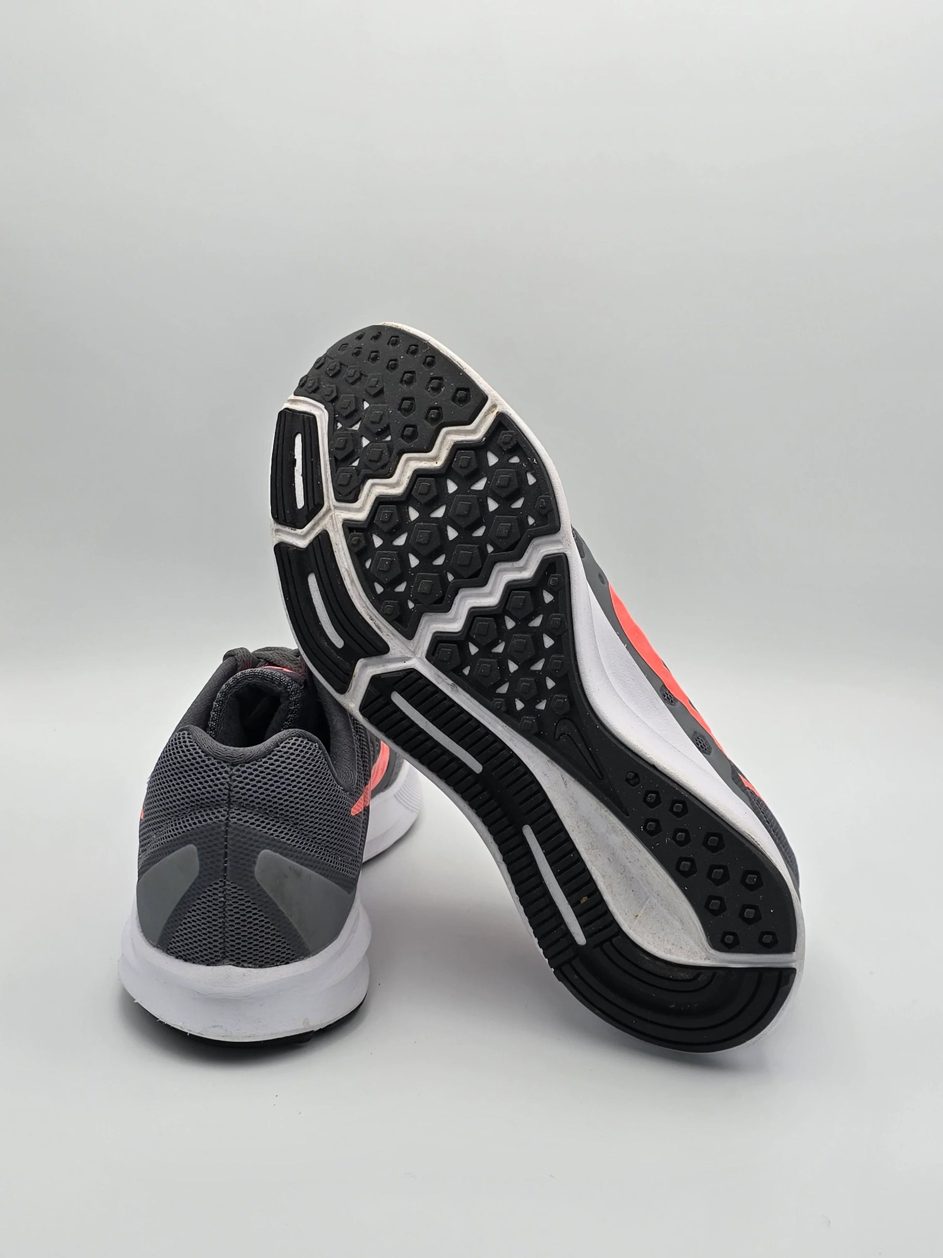 Graue Laufschuhe mit weißer Sohle und pinken Details auf weißem Hintergrund, sportliche Mode