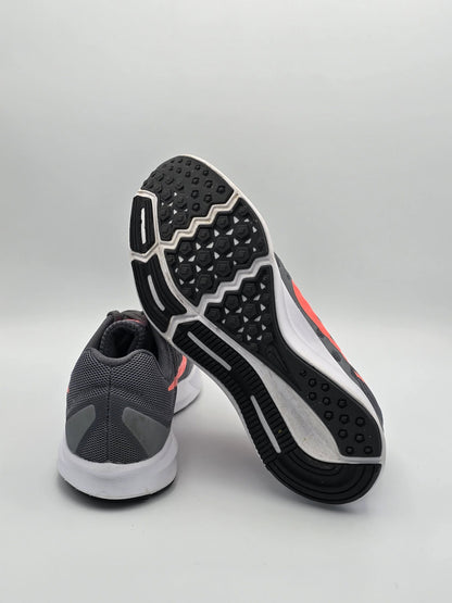 Graue Laufschuhe mit weißer Sohle und pinken Details auf weißem Hintergrund, sportliche Mode