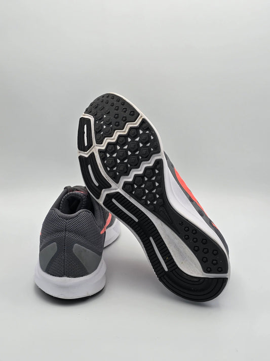 Graue Laufschuhe mit weißer Sohle und pinken Details auf weißem Hintergrund, sportliche Mode