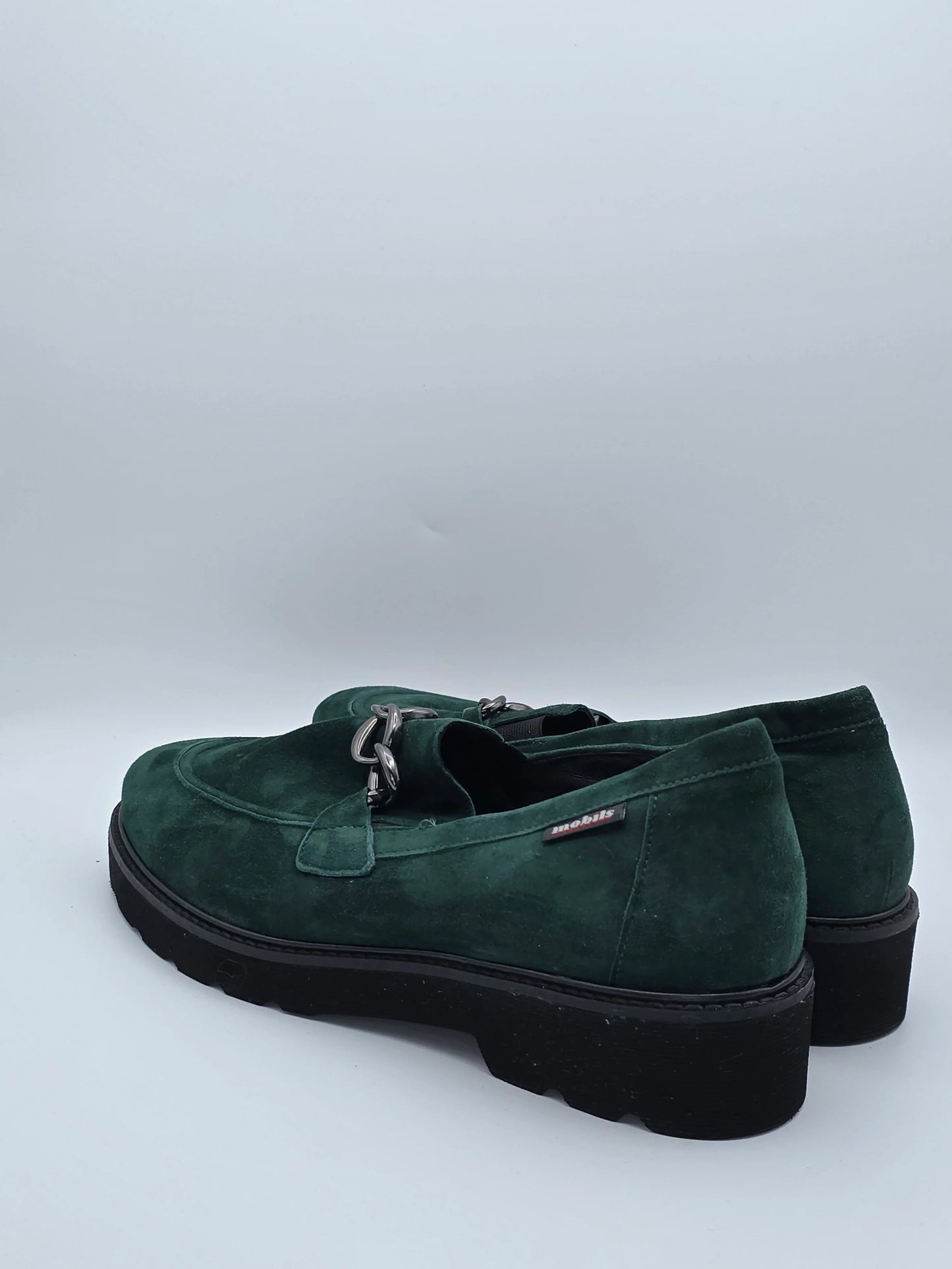 Dunkelgrüne Wildleder-Loafer mit silberner Kette und Profilsohle auf weißem Hintergrund