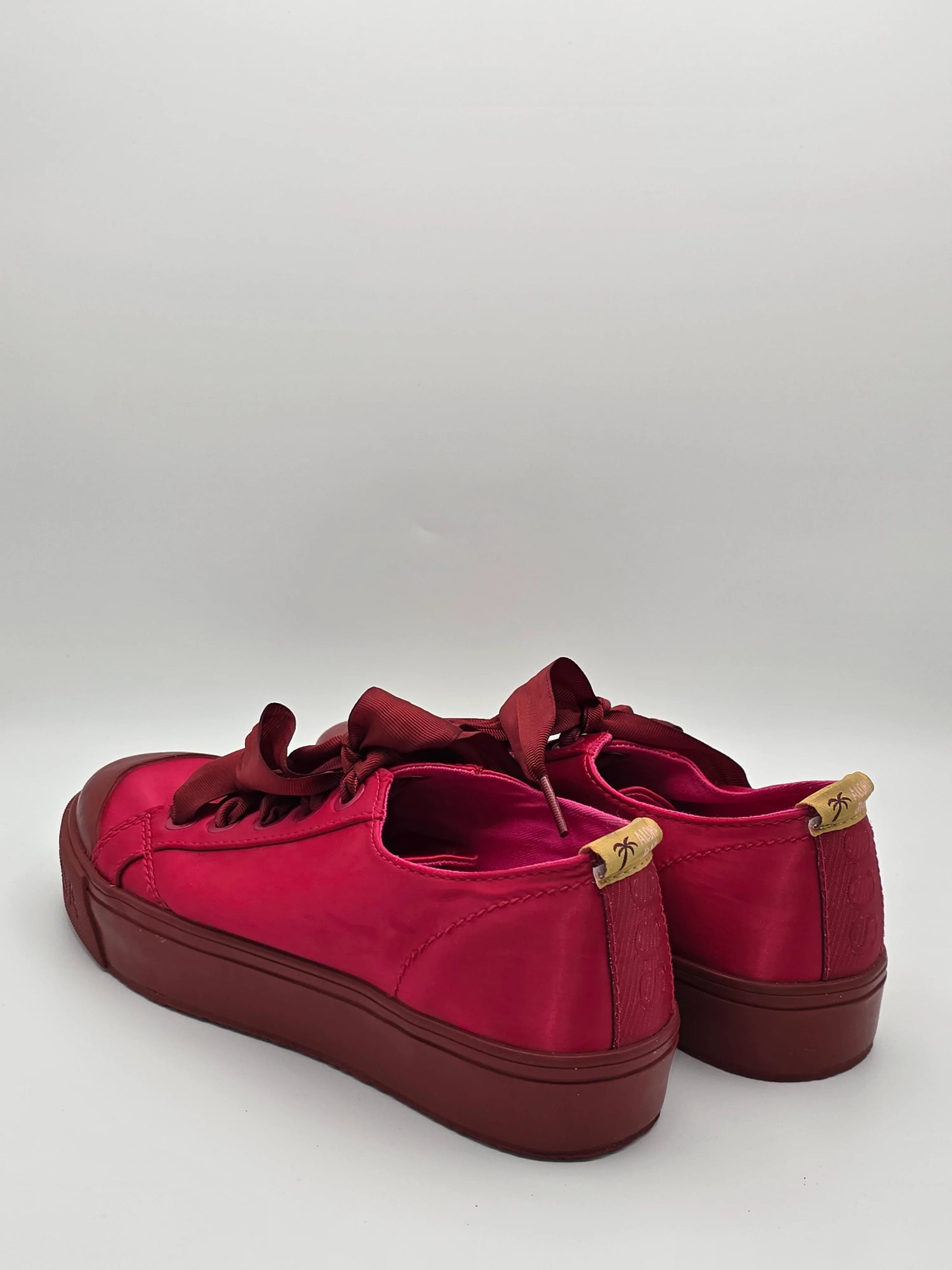 Modische Damen Sneaker in Rot mit Schleifen und braunen Details auf weißem Hintergrund