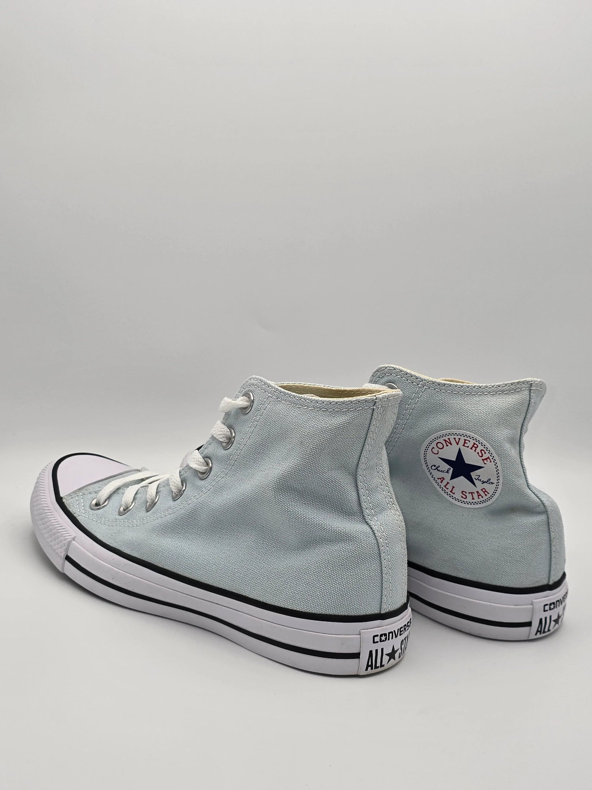 Weiße High-Top Sneaker aus Canvas mit Schnürung und All Star Logo auf weißem Hintergrund.