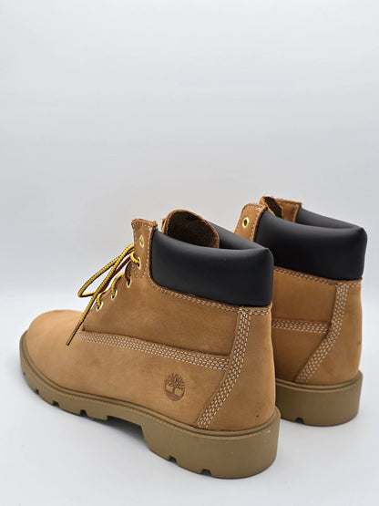Zwei braune Nubukleder-Boots mit schwarzem Schaft und gelben Schnürsenkeln auf weißem Hintergrund