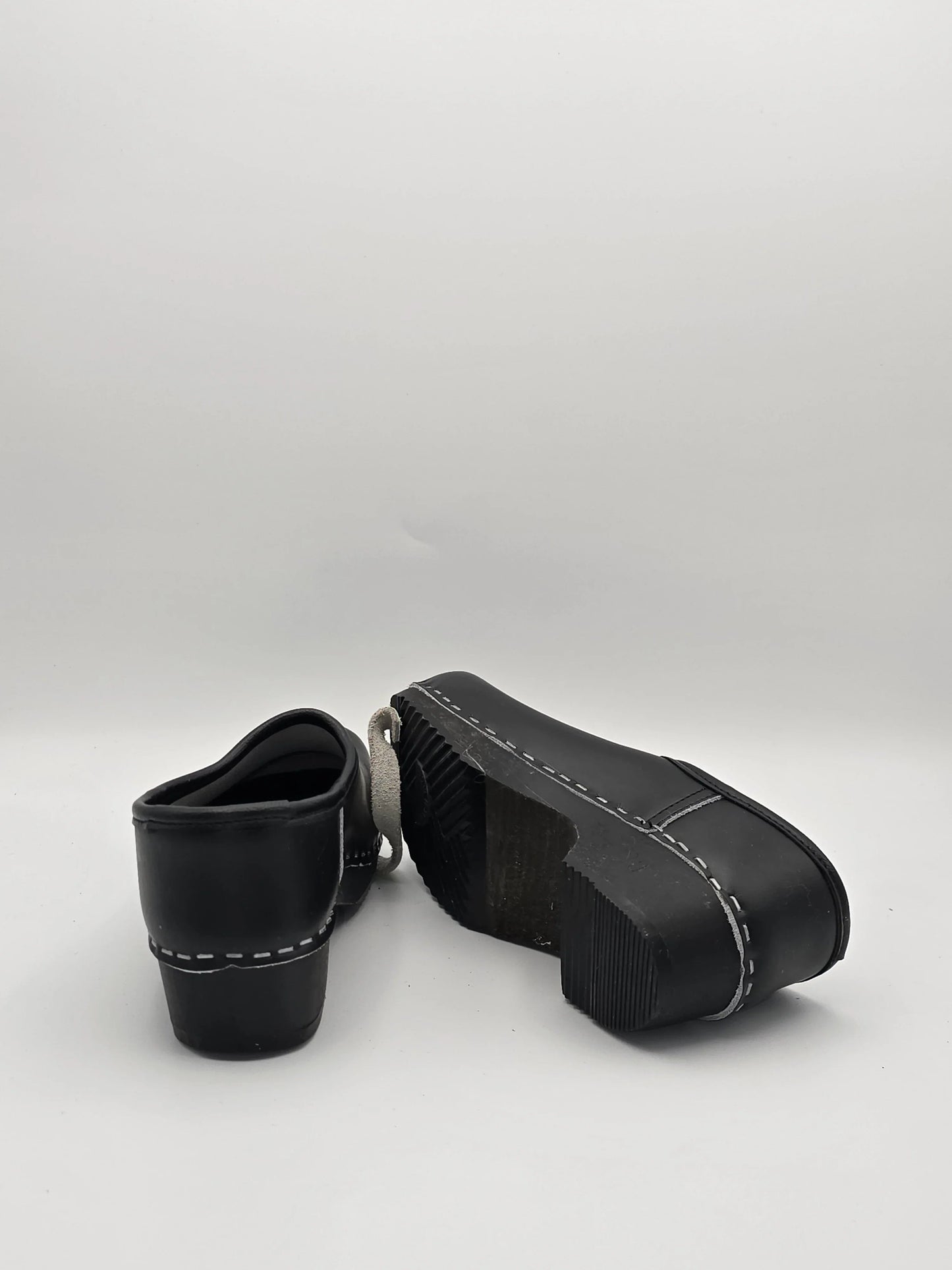 Schwarze Lederschuhe mit dicker Sohle und weißer Ziernaht, Mode Schuhe auf weißem Hintergrund