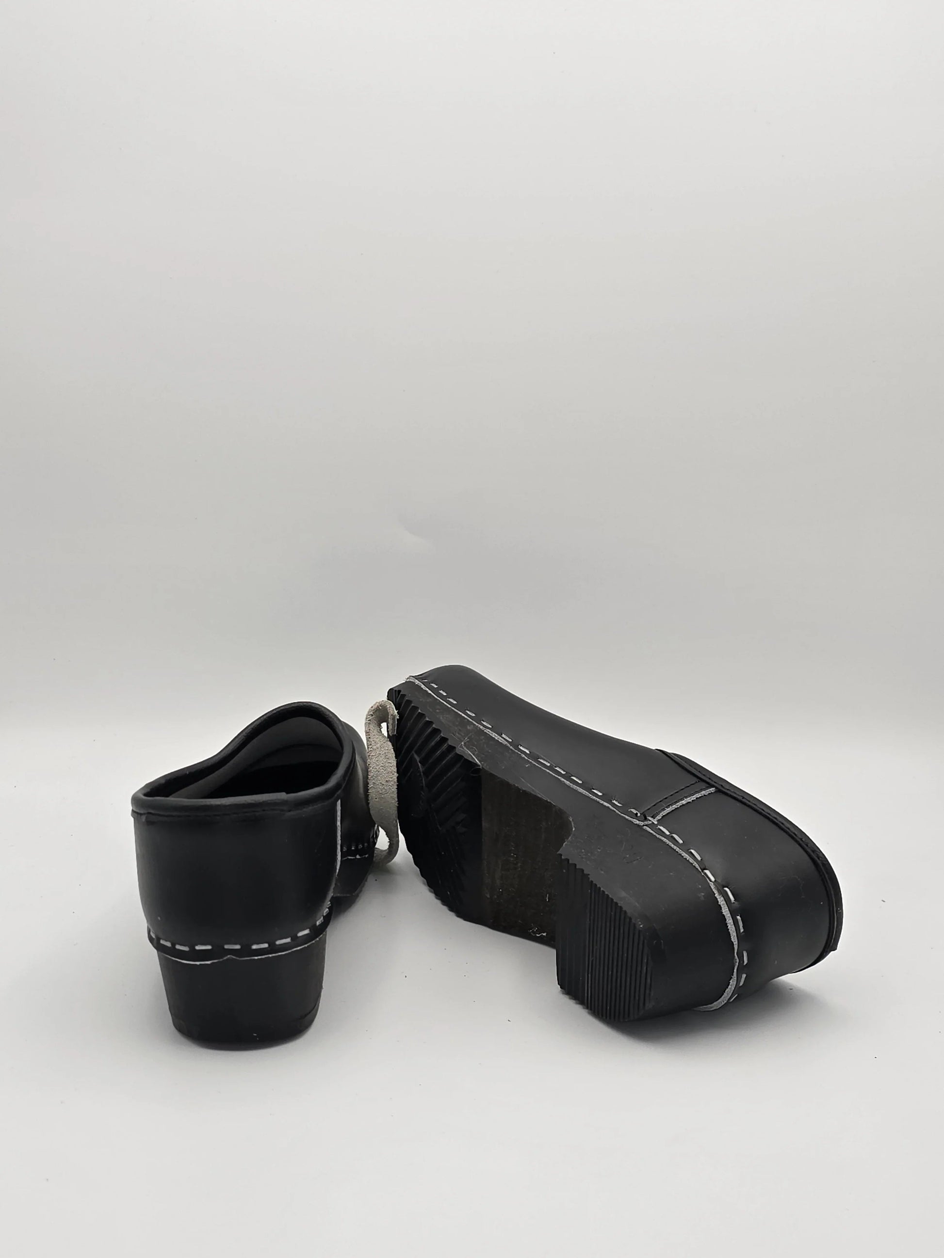 Schwarze Lederschuhe mit dicker Sohle und weißer Ziernaht, Mode Schuhe auf weißem Hintergrund