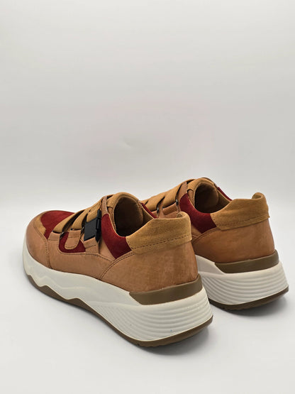 Moderne Sneaker aus braunem und rotem Wildleder mit dicker weißer Sohle auf weißem Hintergrund