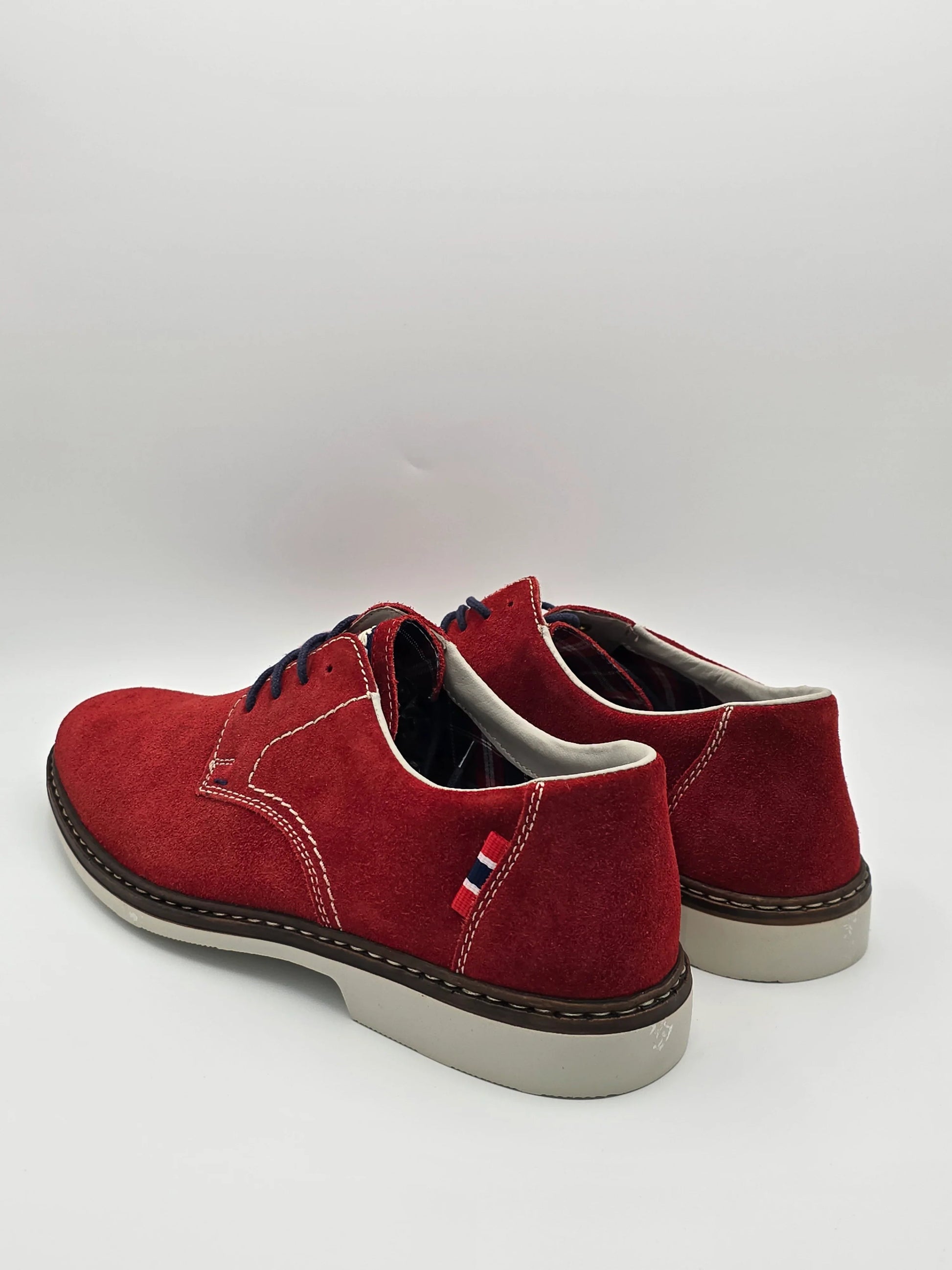 Rote Wildleder-Schuhe mit weißen Nähten, Schnürung und heller Sohle auf weißem Hintergrund