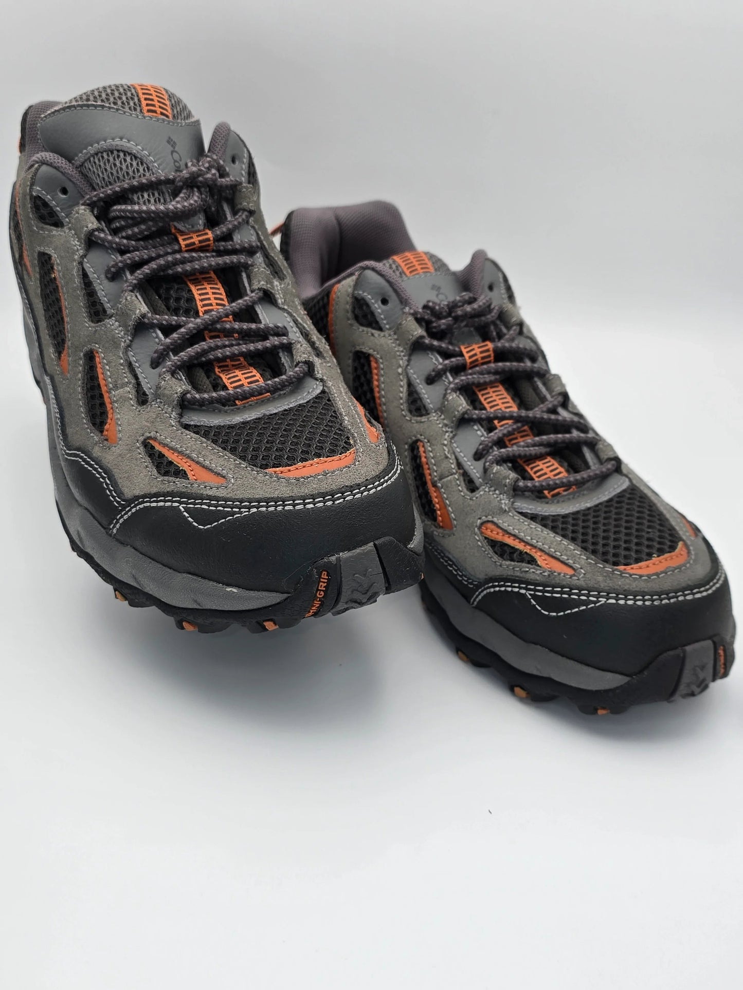 Graue Outdoor Sneaker mit orangen Details und robuster Sohle auf weißem Hintergrund