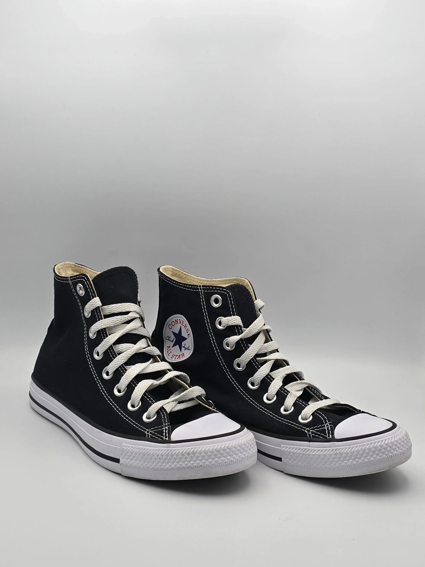 Schwarze High-Top-Sneaker aus Canvas mit weißer Sohle und Schnürsenkeln auf hellem Hintergrund