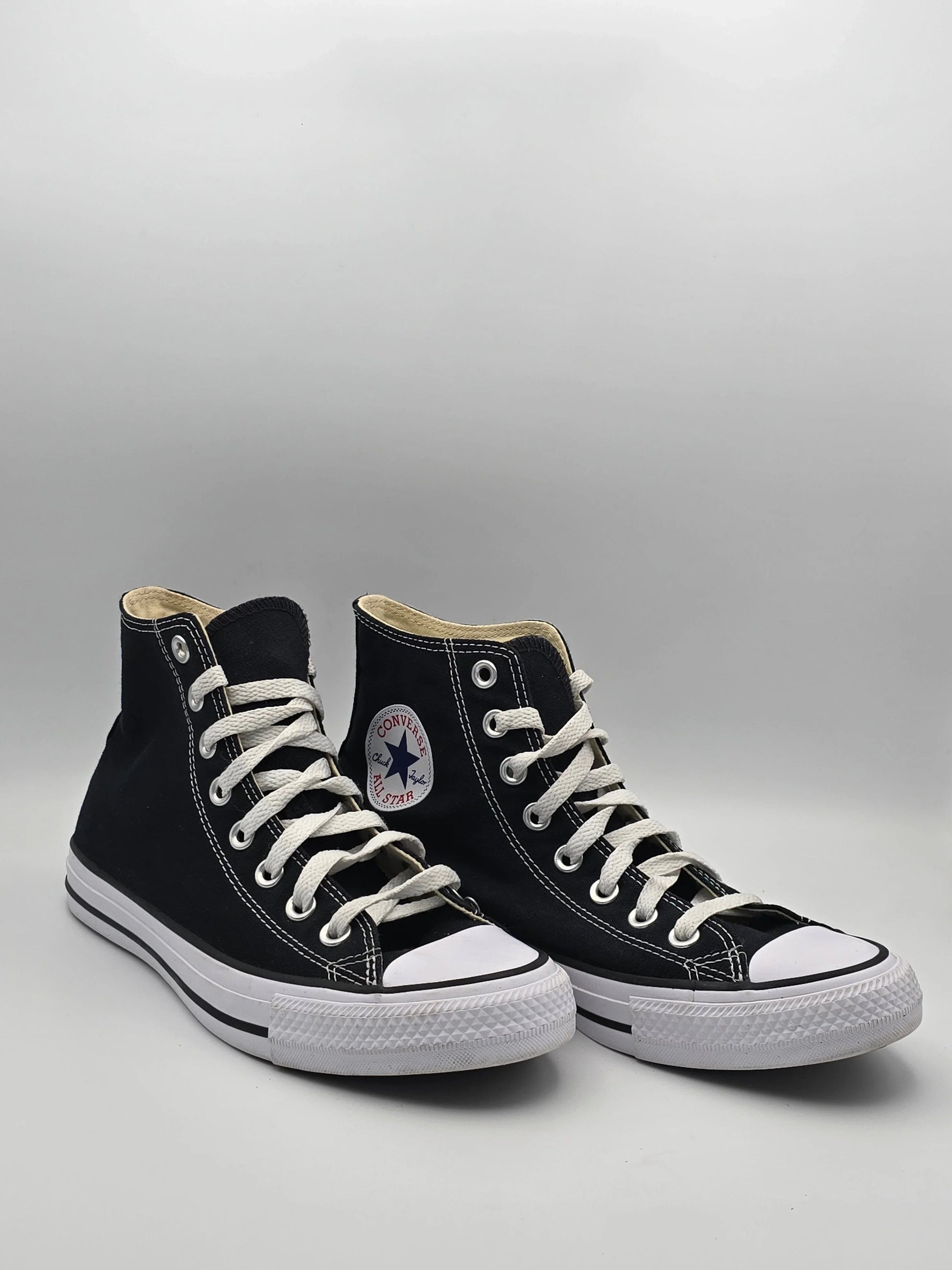 Schwarze High-Top-Sneaker aus Canvas mit weißer Sohle und Schnürsenkeln auf hellem Hintergrund