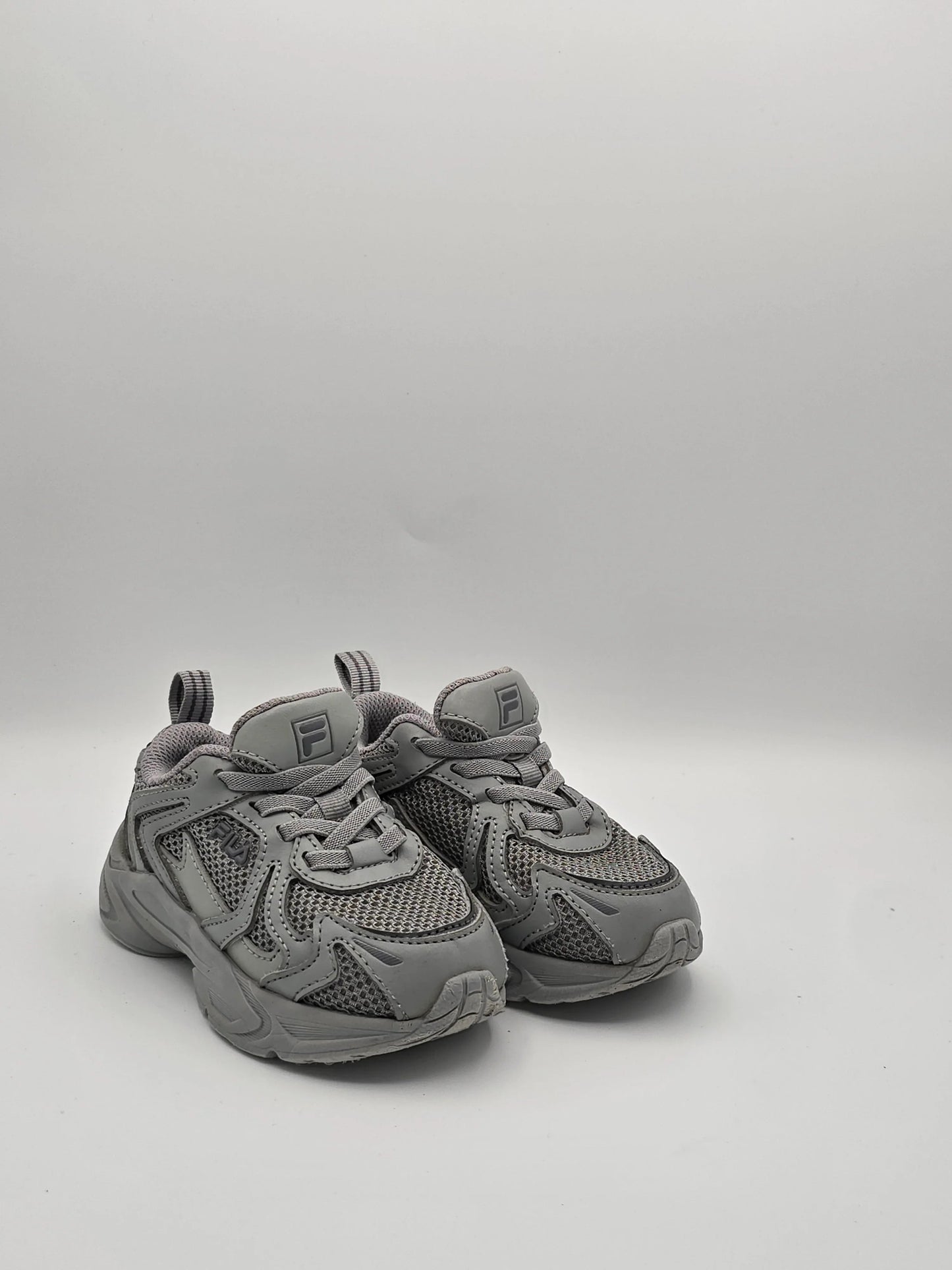 Graue Sneaker aus Mesh und Kunstleder mit Profilsohle, sportlicher Unisex-Schuh auf weißem Hintergrund