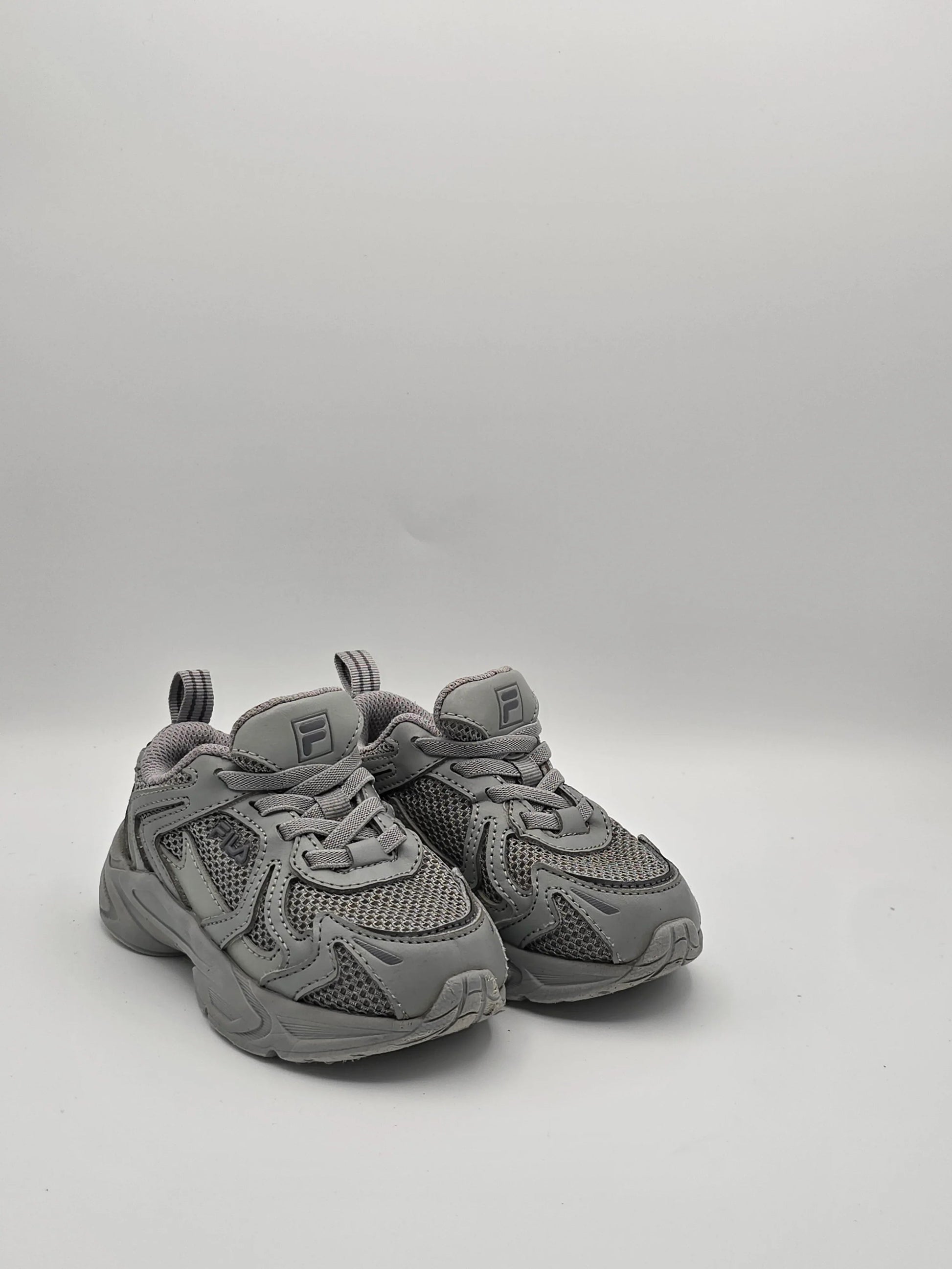 Graue Sneaker aus Mesh und Kunstleder mit Profilsohle, sportlicher Unisex-Schuh auf weißem Hintergrund