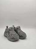 Graue Sneaker aus Mesh und Kunstleder mit Profilsohle, sportlicher Unisex-Schuh auf weißem Hintergrund