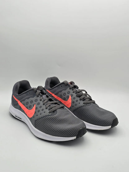 Graue Sportschuhe mit Netzstruktur, leuchtend rotem Logo und weißer Sohle auf neutralem Hintergrund