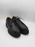 Schwarze Lederschuhe mit Profilsohle und Schnürsenkeln auf weißem Hintergrund