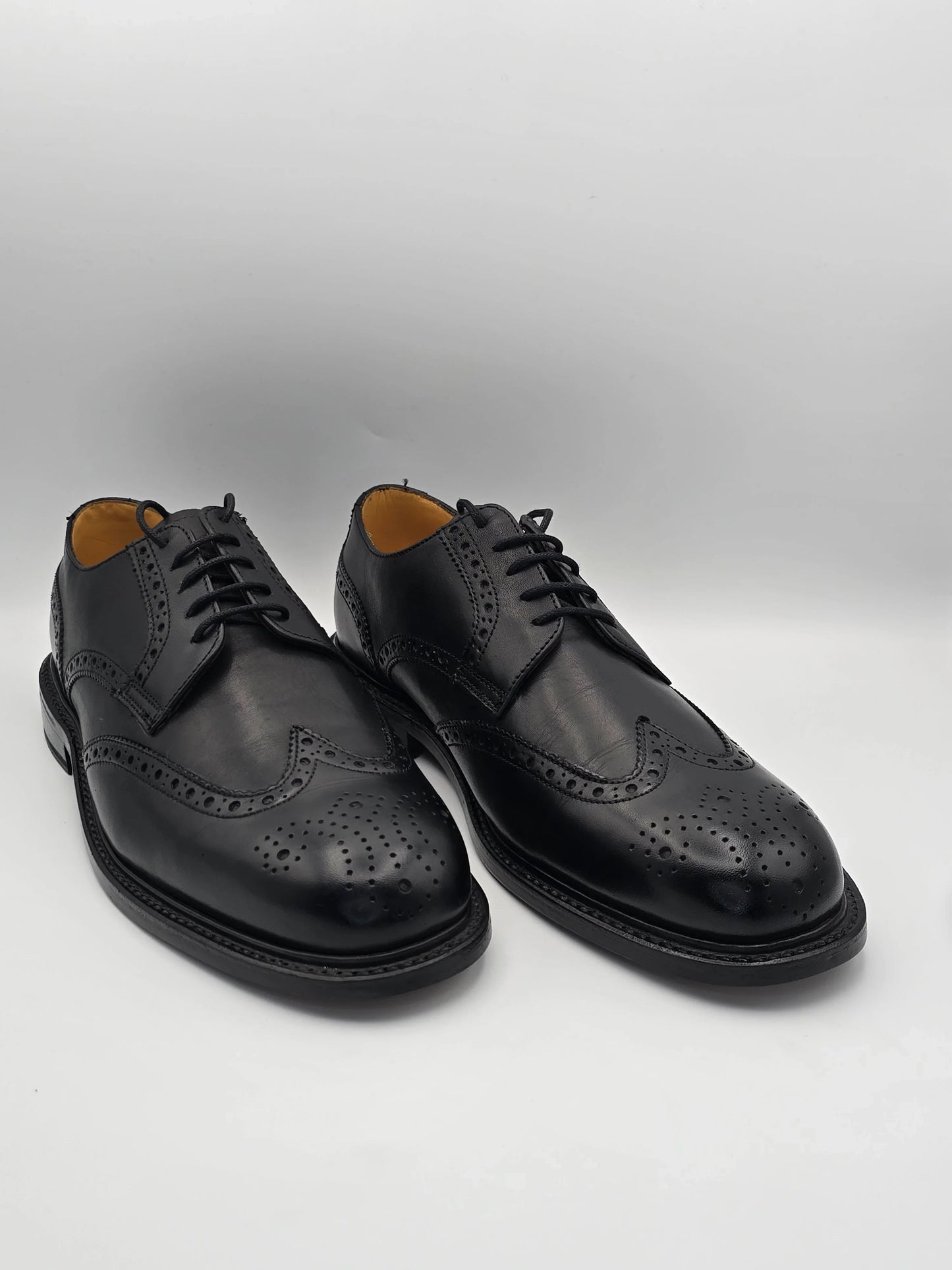 Elegante schwarze Lederschuhe mit Broguing-Lochmuster für Herren, auf weißem Hintergrund
