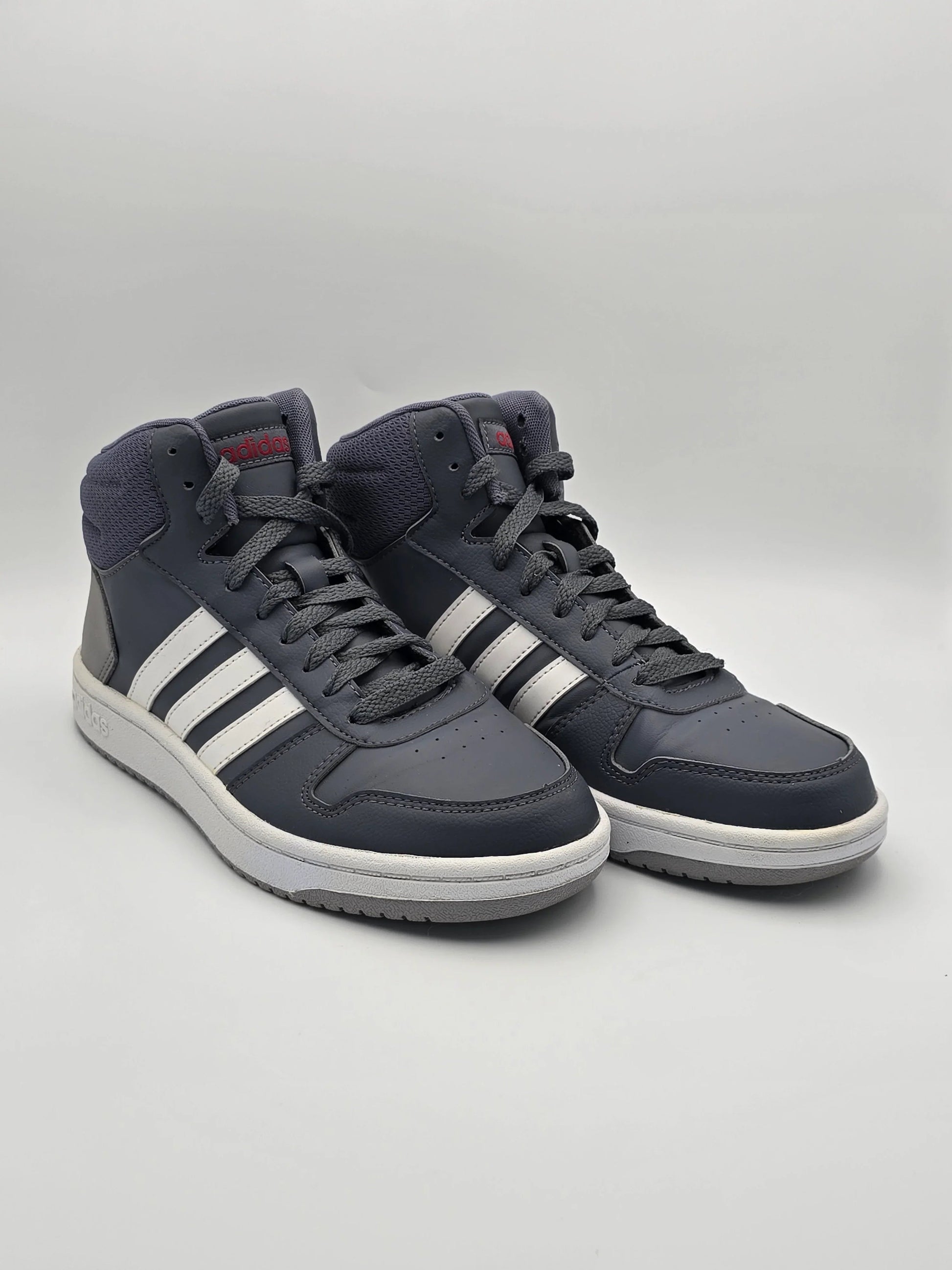 Dunkelgraue Sneaker mit weißen Streifen, sportlicher Look, modische Schuhe auf weißem Hintergrund