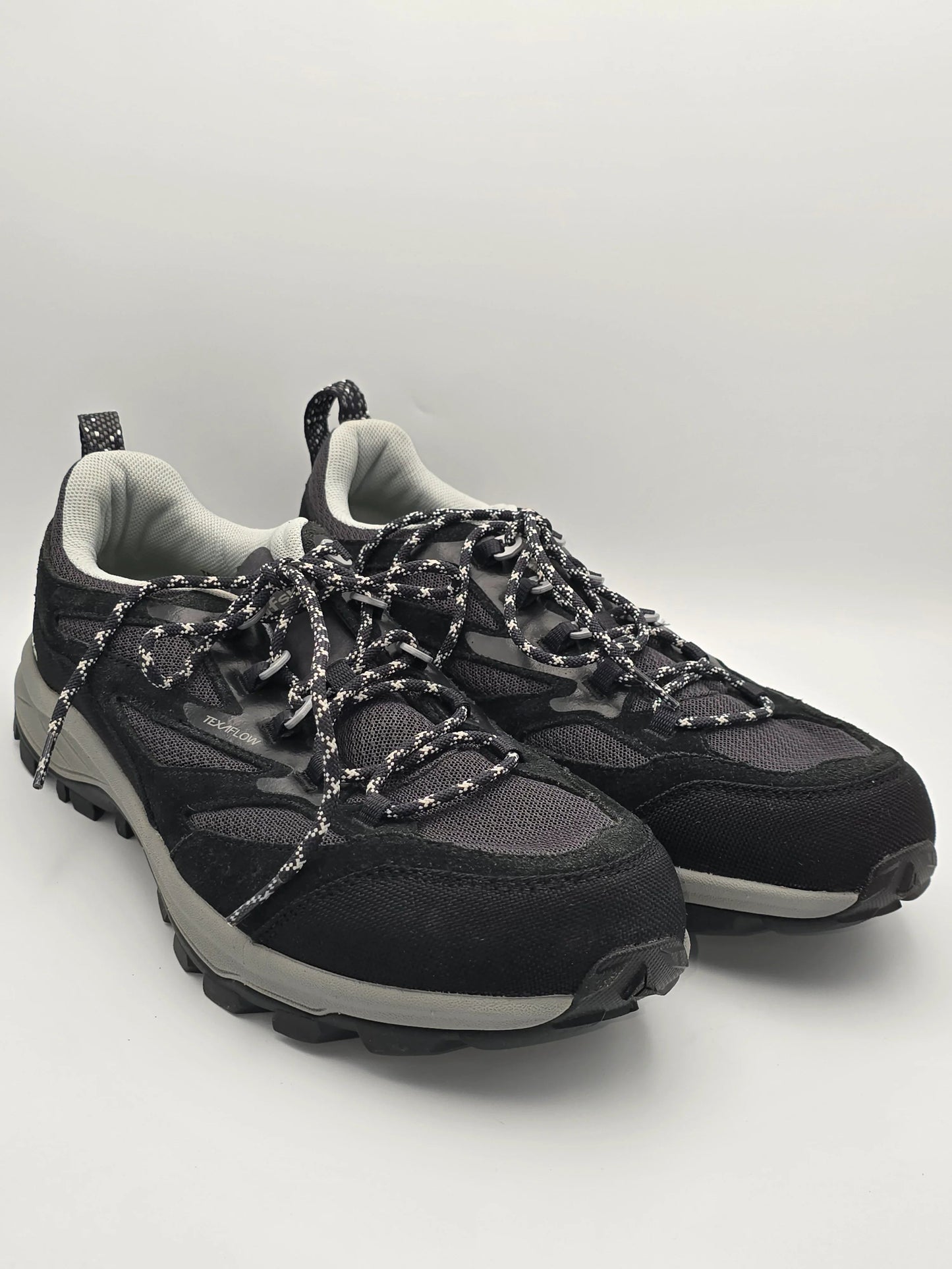 Schwarze Trekking-Sneaker mit dicker Sohle und gemusterten Schnürsenkeln auf weißem Hintergrund