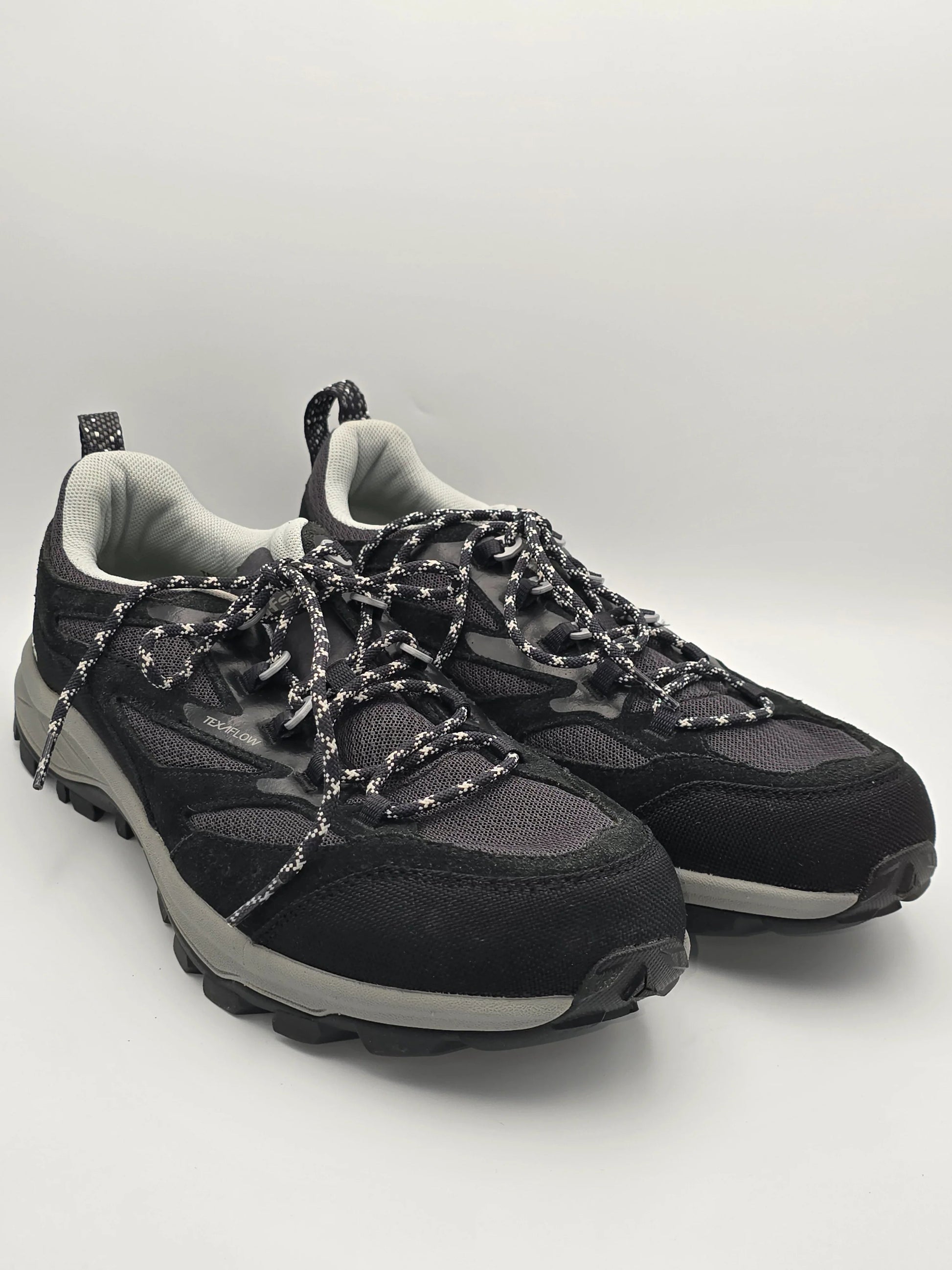 Schwarze Trekking-Sneaker mit dicker Sohle und gemusterten Schnürsenkeln auf weißem Hintergrund