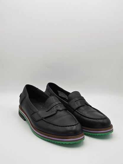 Schwarze Leder Slipper mit grün-lila Sohle, modische Damen Schuhe auf weißem Hintergrund