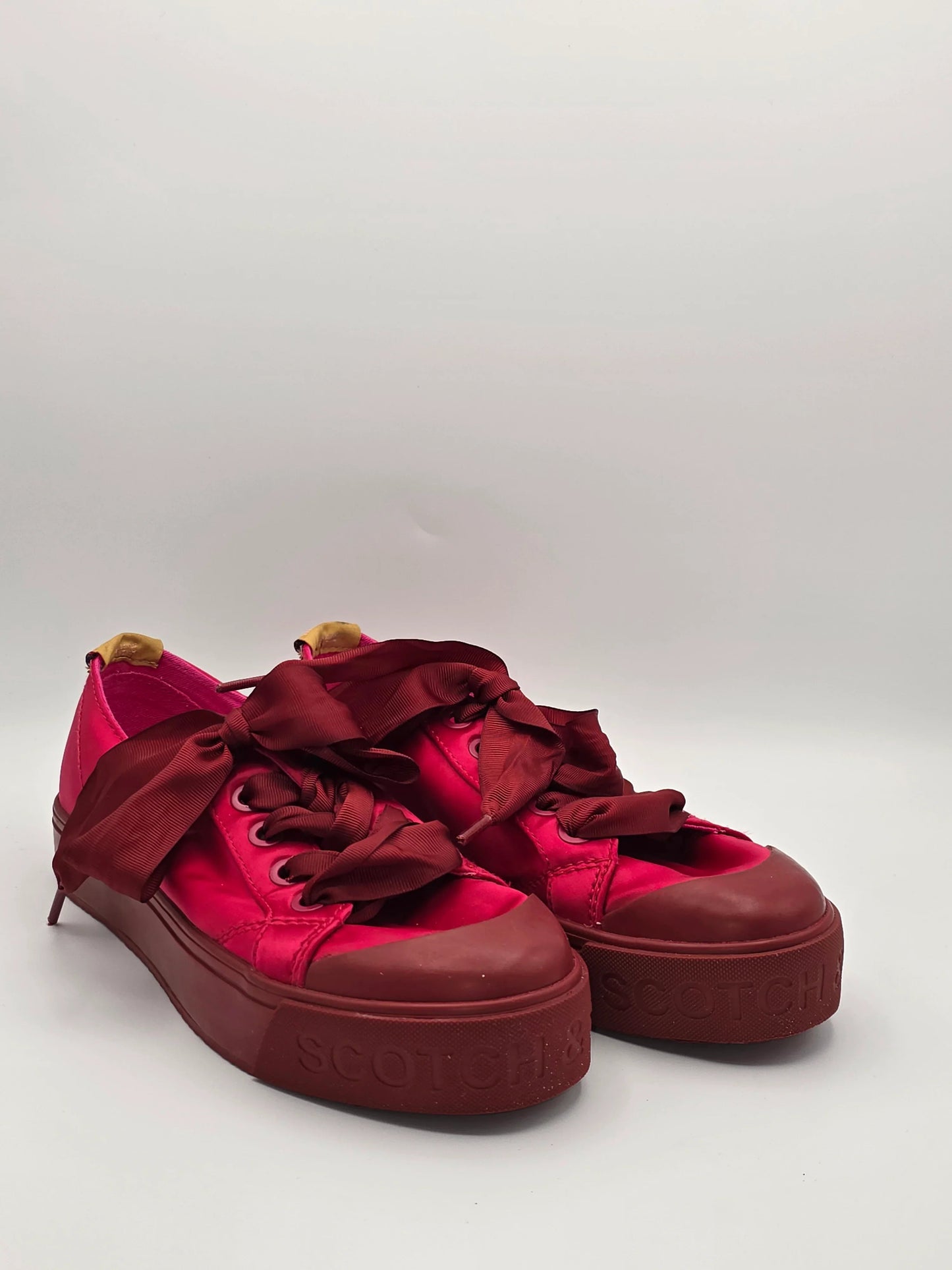 Rote Damen Sneaker mit breiten Satinschnürsenkeln und Plateausohle auf weißem Hintergrund